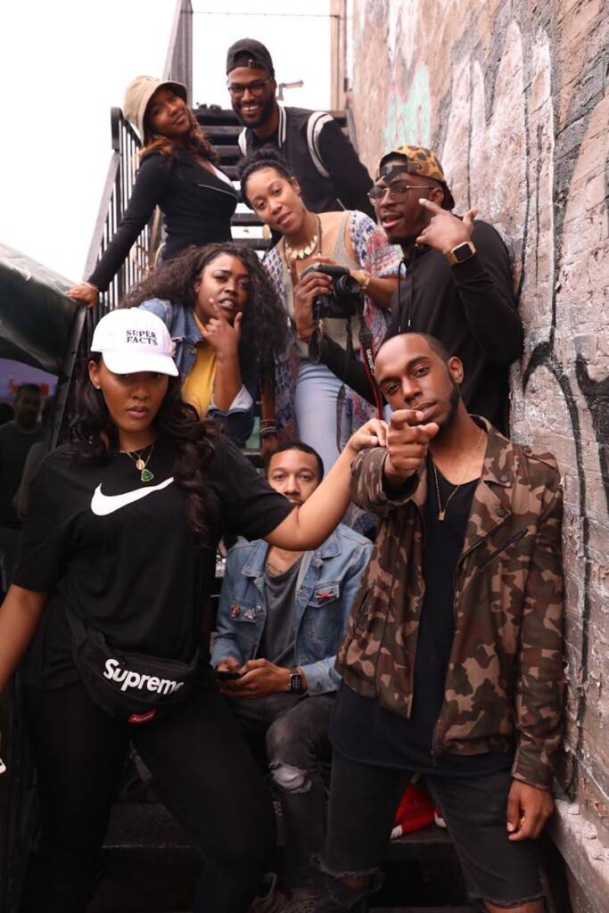 A diverse group of young adults having fun and posing on an outdoor staircase.