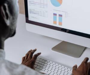 Businessman analyzing charts and data on desktop computer in office setting.